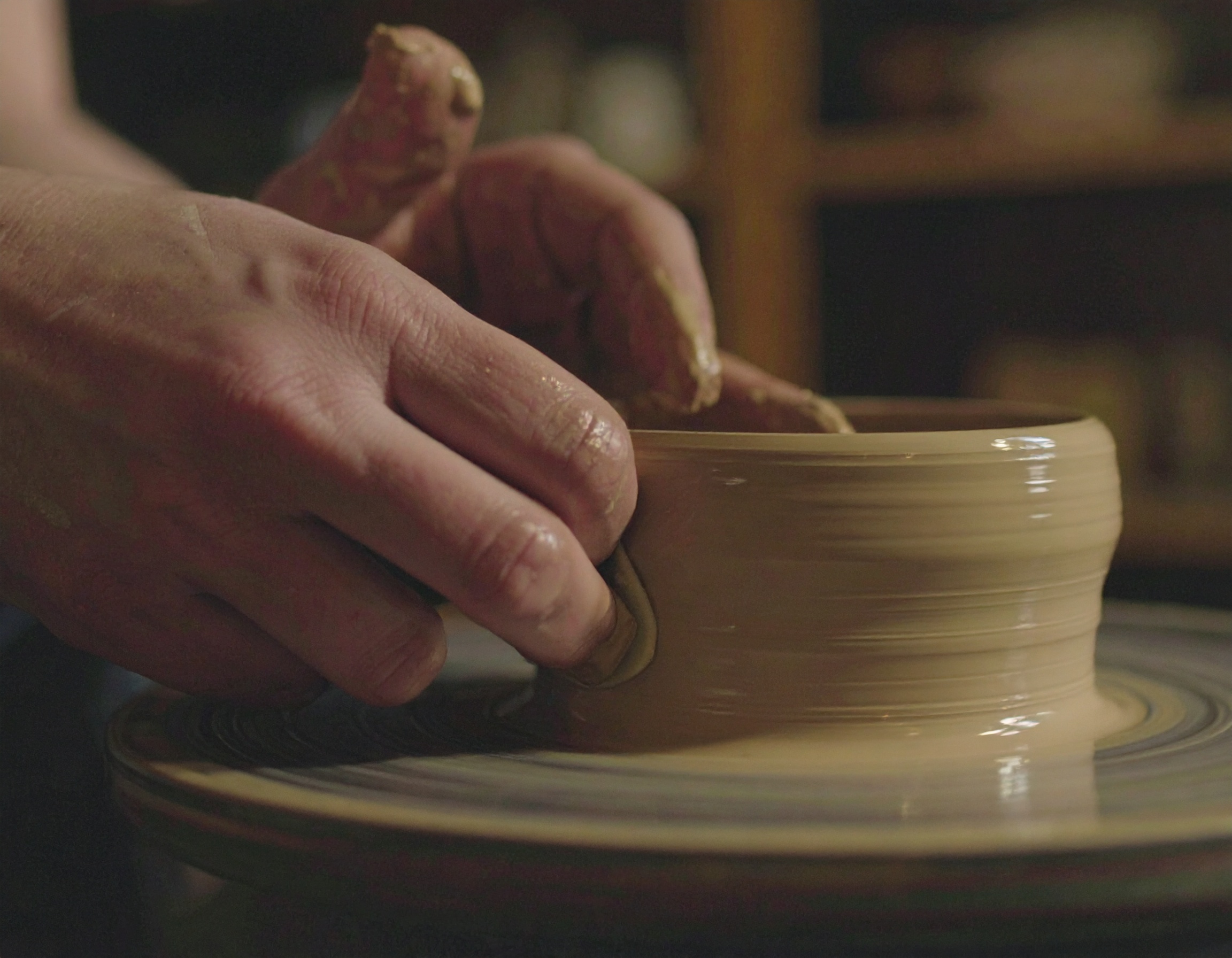 Hands shaping pottery on a wheel